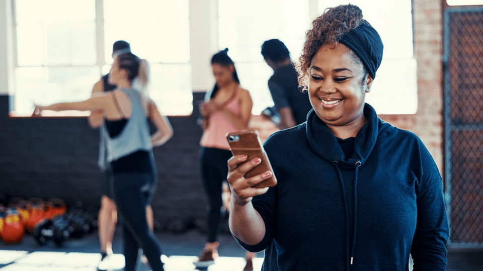 woman using at fitness app on her smart phone in gym class