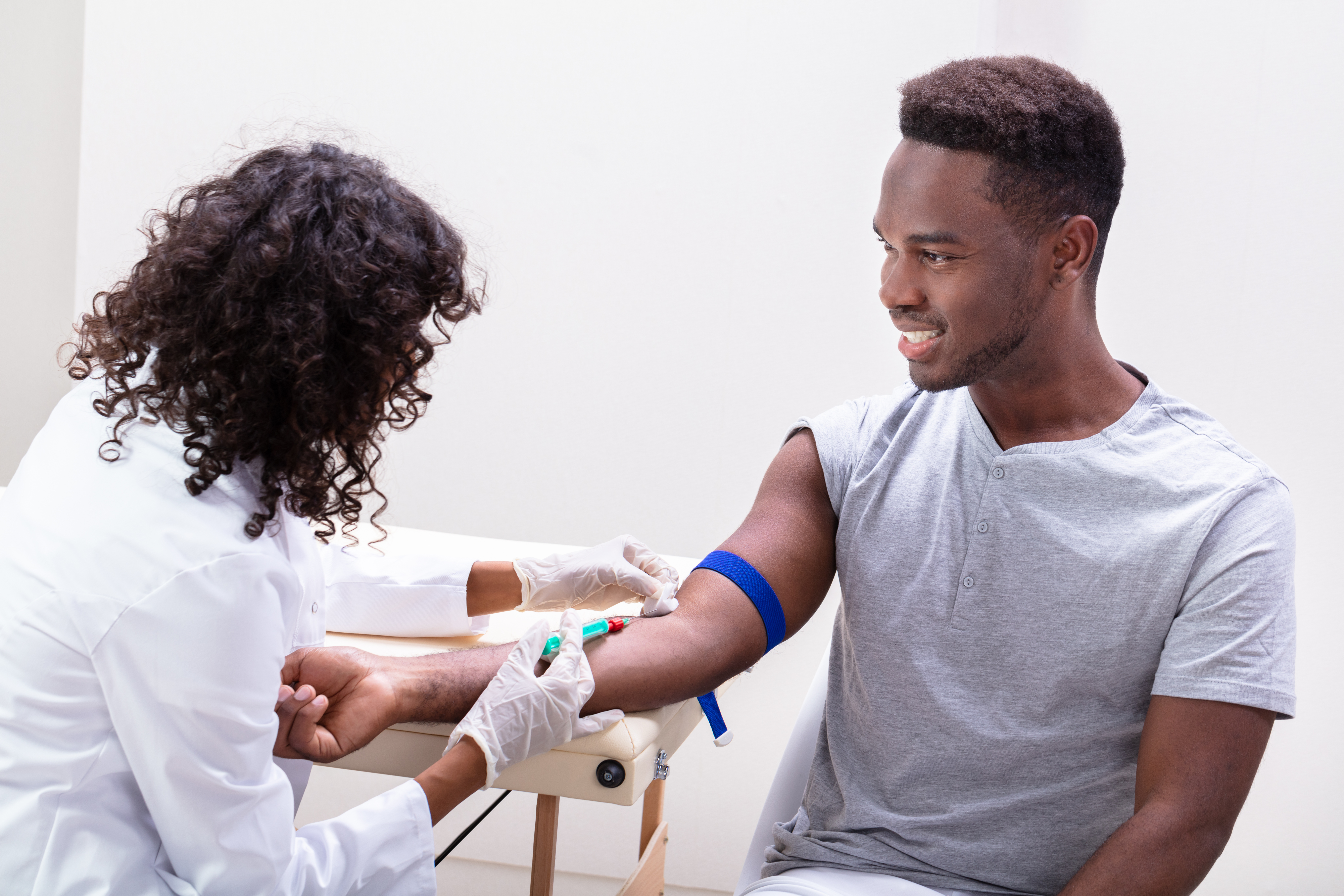 a clinician is shown drawing blood from a patient