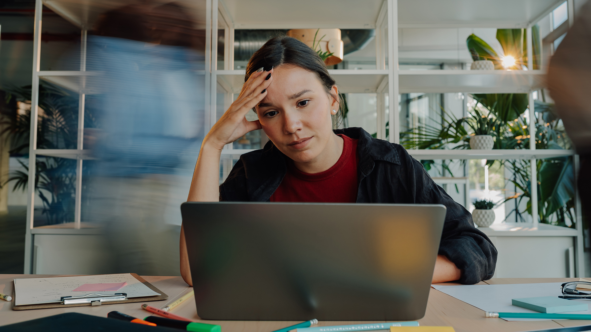 a woman is shown working at a laptop while looking burned out and stressed