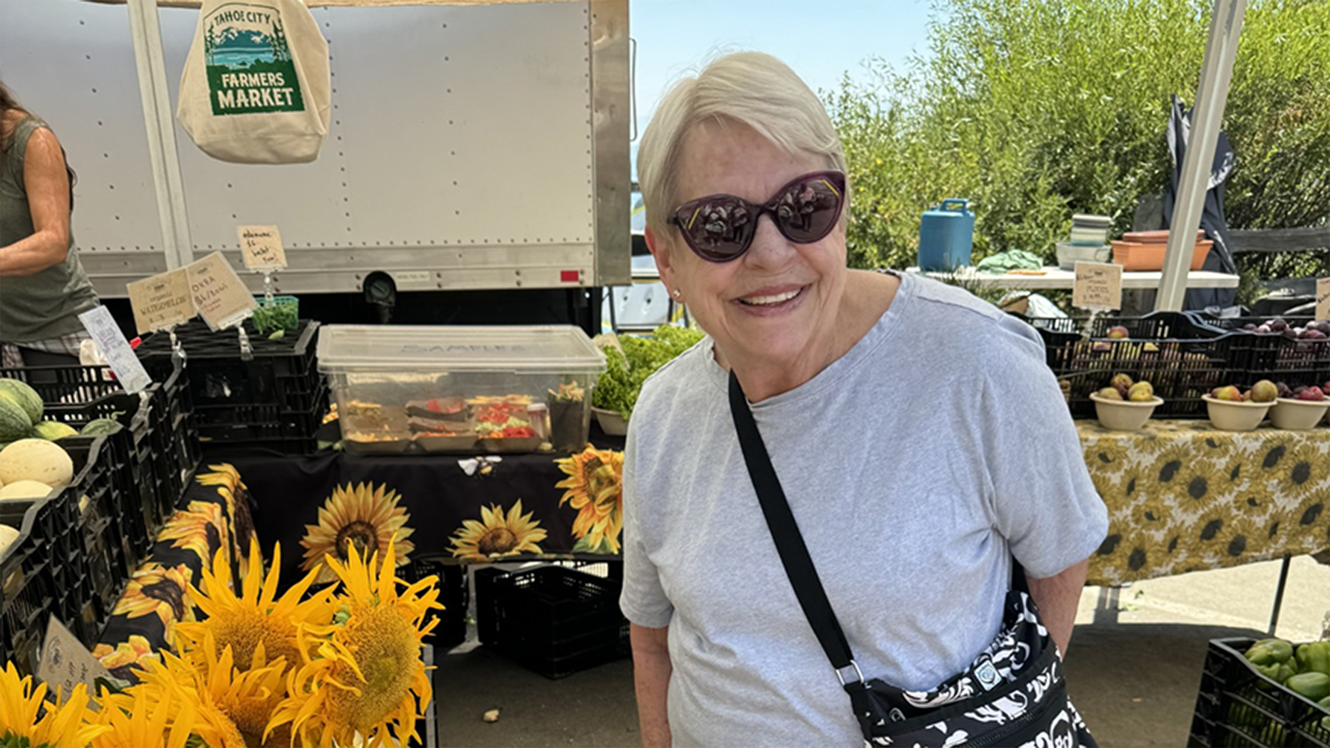 Kathy wearing sunglasses and smiling at the camera while out at a farmers market after successful aortic aneurysm surgery