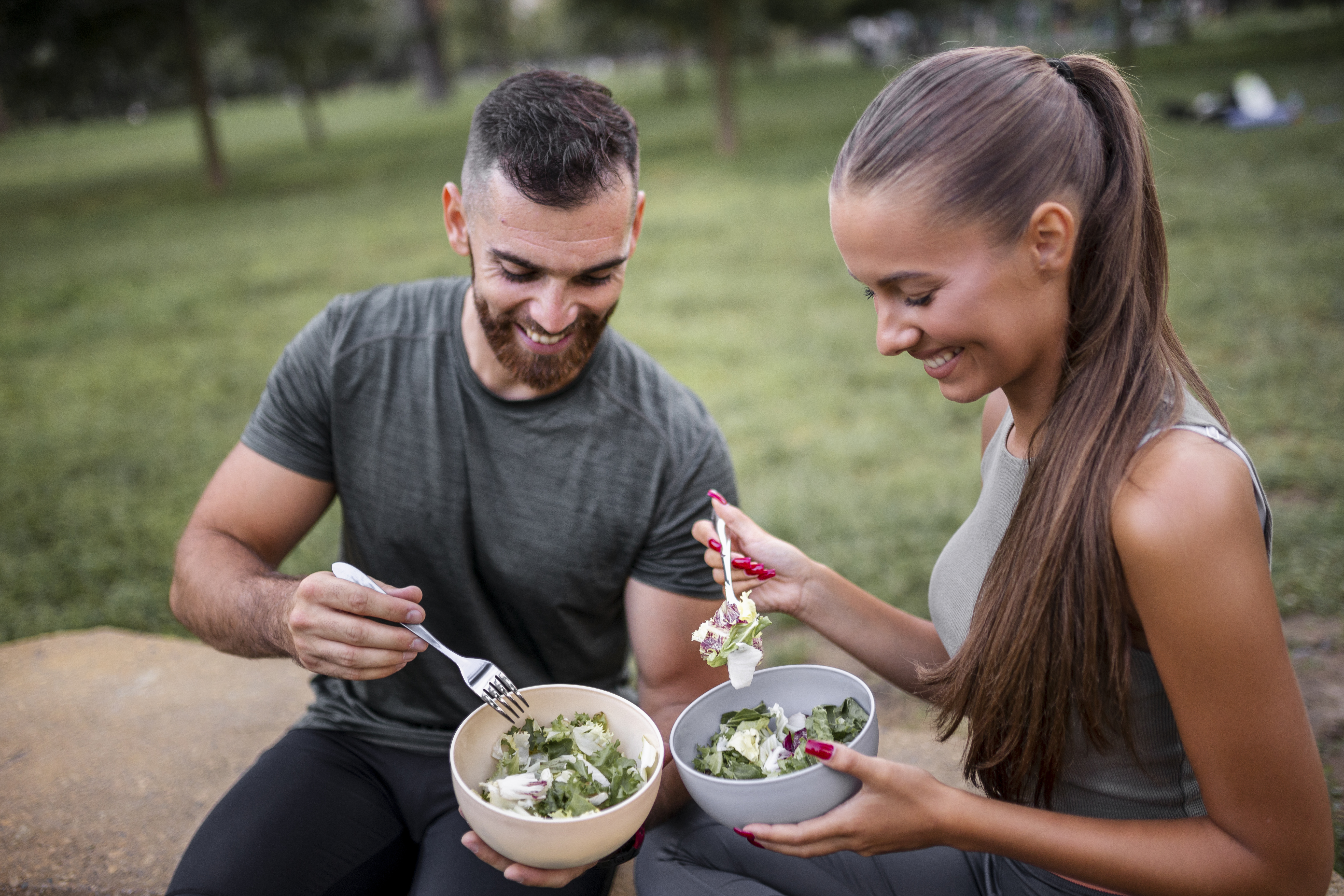 Happy sporty couple eating vegetable salad after intensive workout