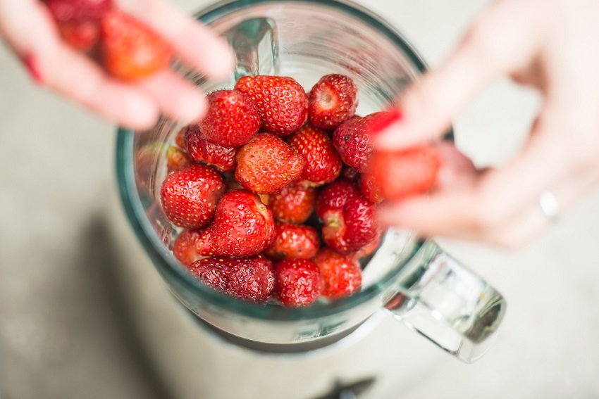 Woman's Hands Placing Strawberries Into a Blender