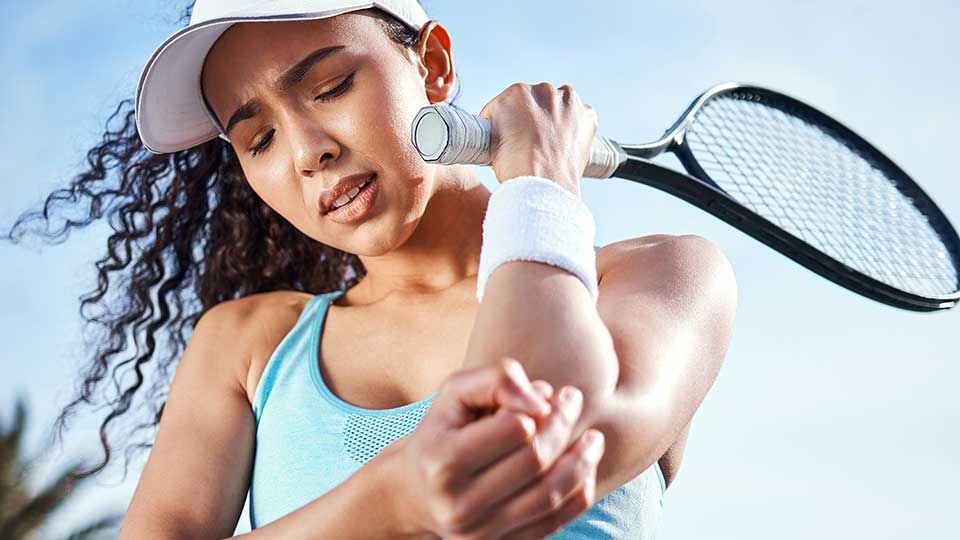 Woman playing tennis and suffering elbow pain