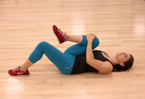 Girl doing a knee to chest stretch